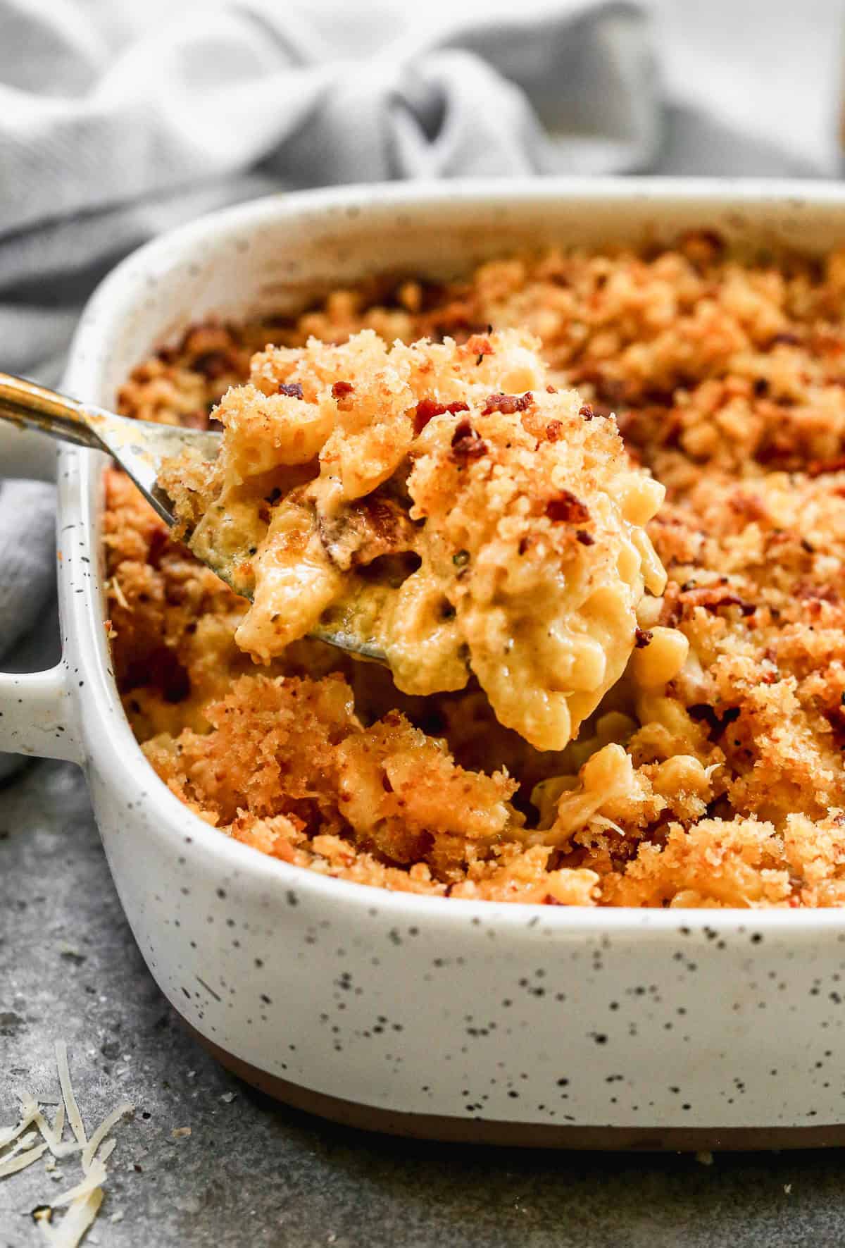 The best Baked Mac and Cheese recipe in a square baking dish with a spoonful being lifted up.