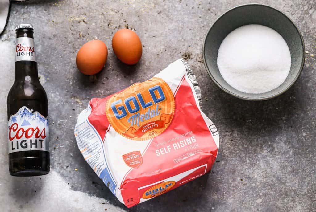 The ingredients needed to make Beer Bread, including Coors Light, self-rising flour, sugar and eggs.