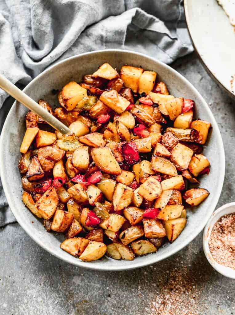 A bowl of crispy Breakfast Potatoes with bell peppers and onion, ready to serve.
