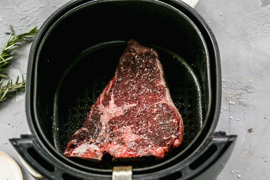 A T-Bone steak in an air fryer, ready to cook.