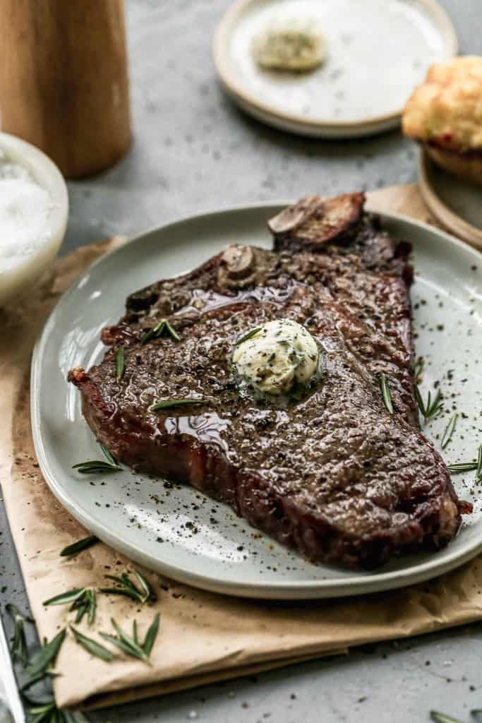 Air Fryer T-Bone Steak served on a plate with herb butter on top.