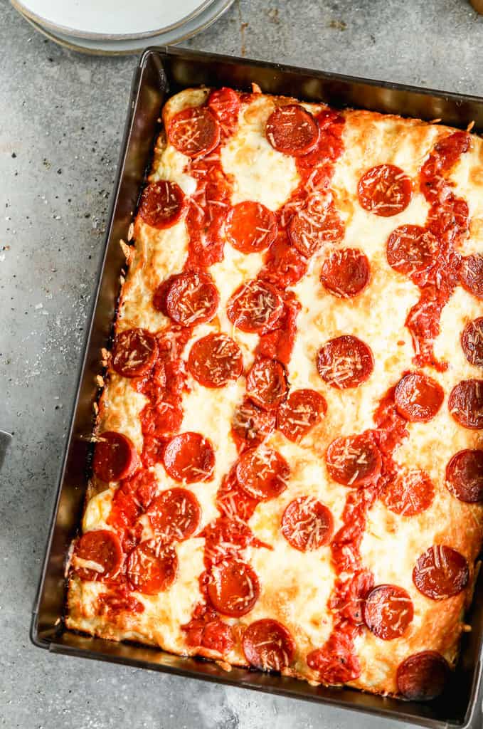 Detroit-style pizza baked in a pan, topped with cheese, sauce and pepperoni.