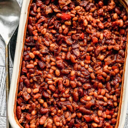 Baked beans in a 9x13 inch baking dish, with a serving spoon on the side.