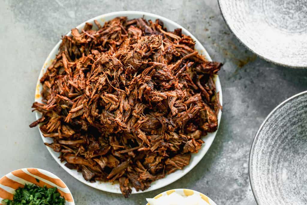 Shredded beef on a plate, ready to make Beef Birria.