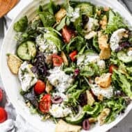 A tomato Burrata Salad recipe with a simple lemon vinaigrette, veggies, fresh herbs, and toasted pita croutons.