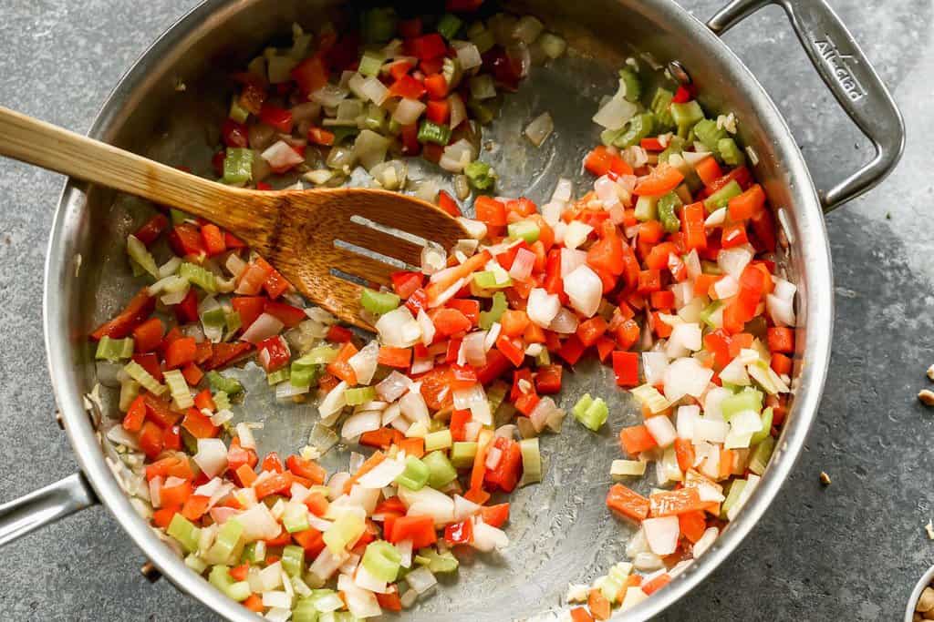 Bell pepper, celery and onion sautéing in a pan.