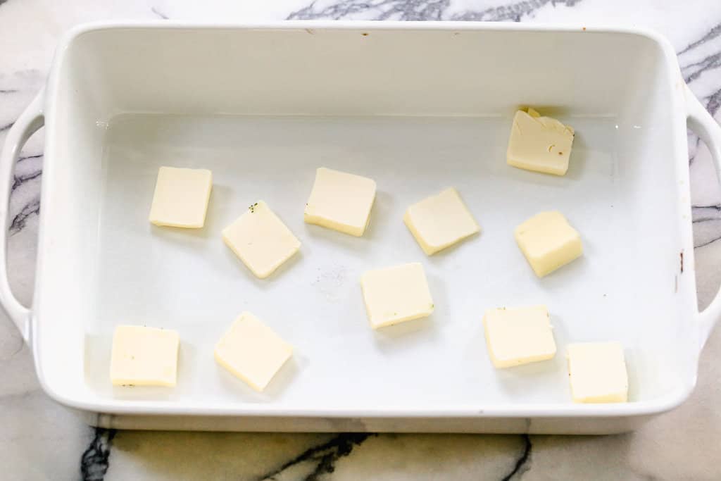 A white rectangle dish with slices of butter in it.