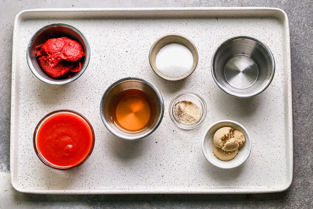 Une plaque à pâtisserie avec tous les ingrédients nécessaires pour faire du ketchup maison.