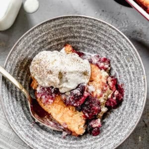An easy Cherry Cobbler recipe served in a bowl with a scoop of vanilla ice cream on top.