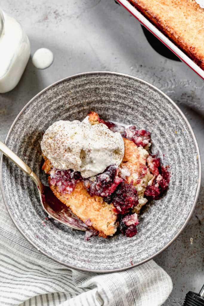 An easy Cherry Cobbler recipe served in a bowl with a scoop of vanilla ice cream on top.