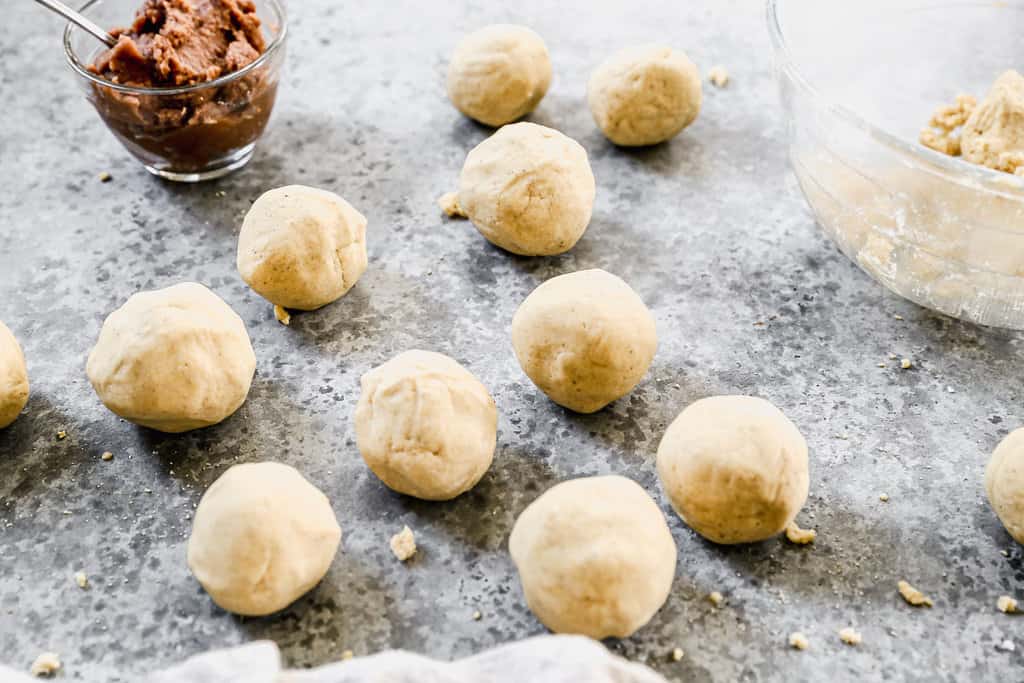 A bunch of golf ball sized balls of dough on a countertop to make Pupusas.