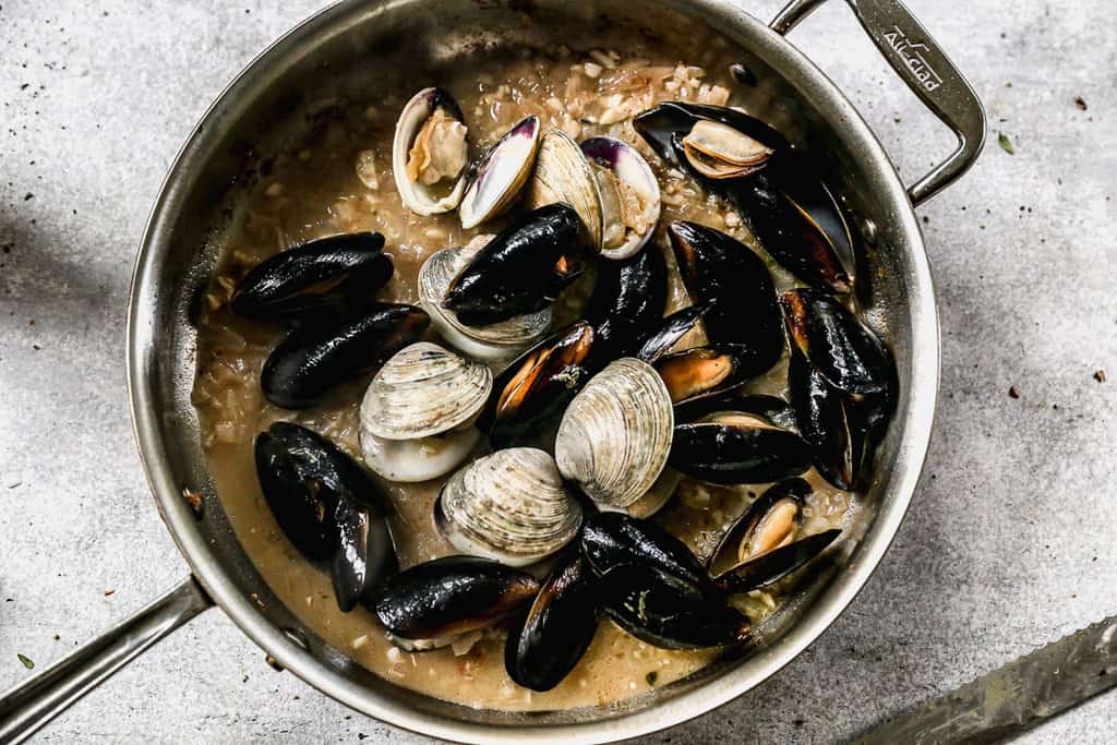 Vongole e cozze in brodo di cipolla rossa, aglio e vino per la pasta ai frutti di mare.