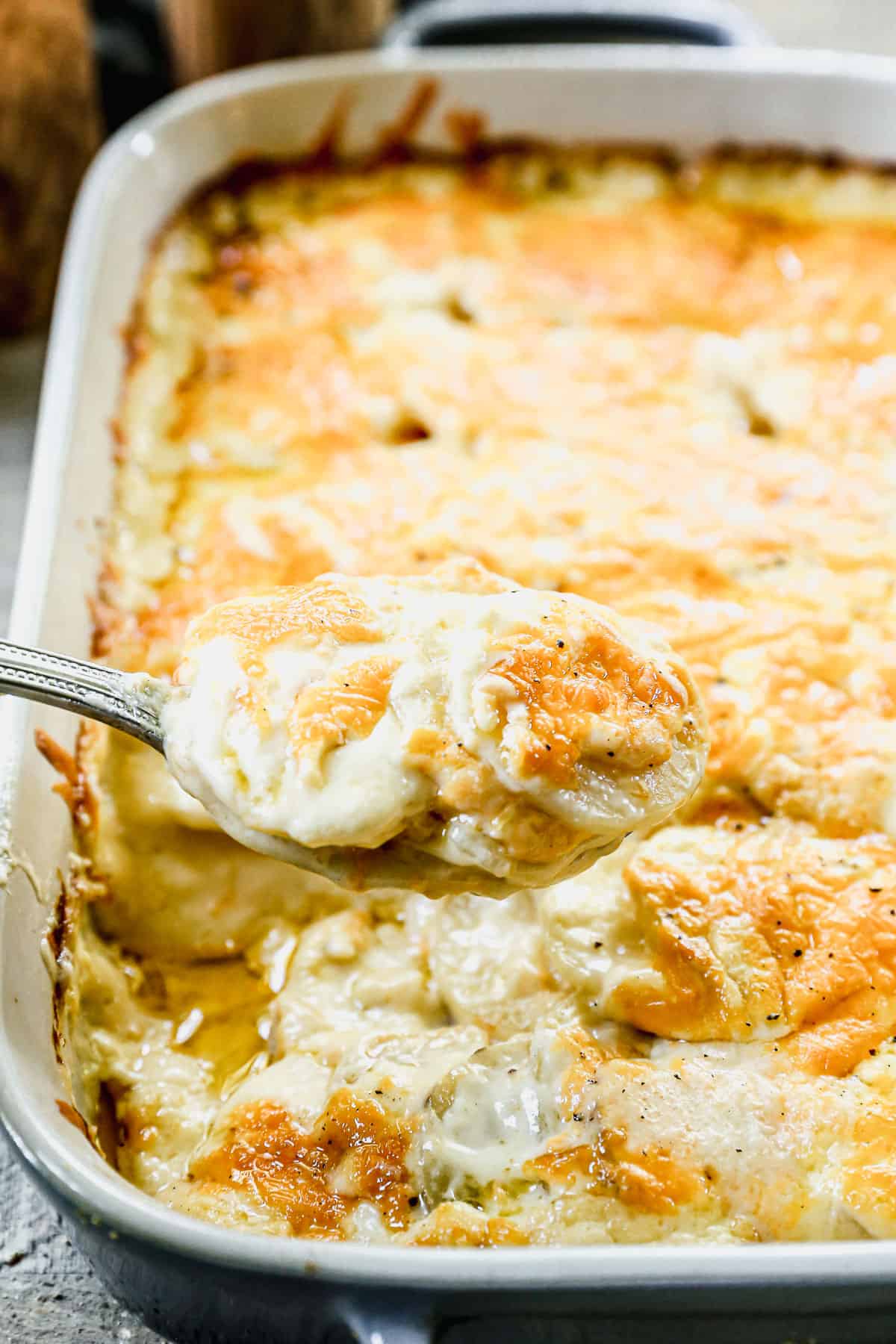 Hot and cheesy Potatoes Au Gratin, with some of it being lifted on a spoon.