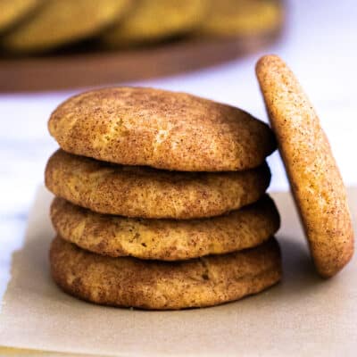 Four Pumpkin Snickerdoodle cookies stacked on top of each other, with one more leaning against them.