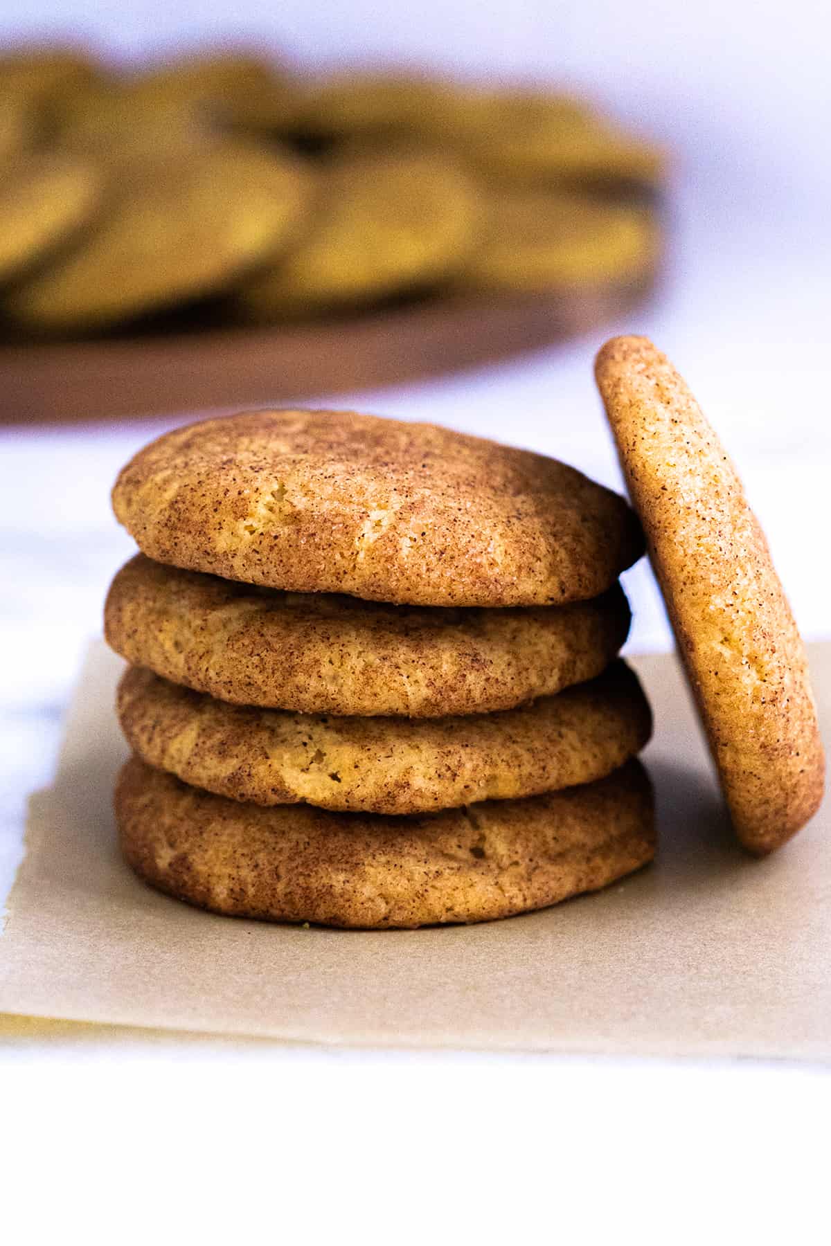 Four Pumpkin Snickerdoodle cookies stacked on top of each other, with one more leaning against them. 