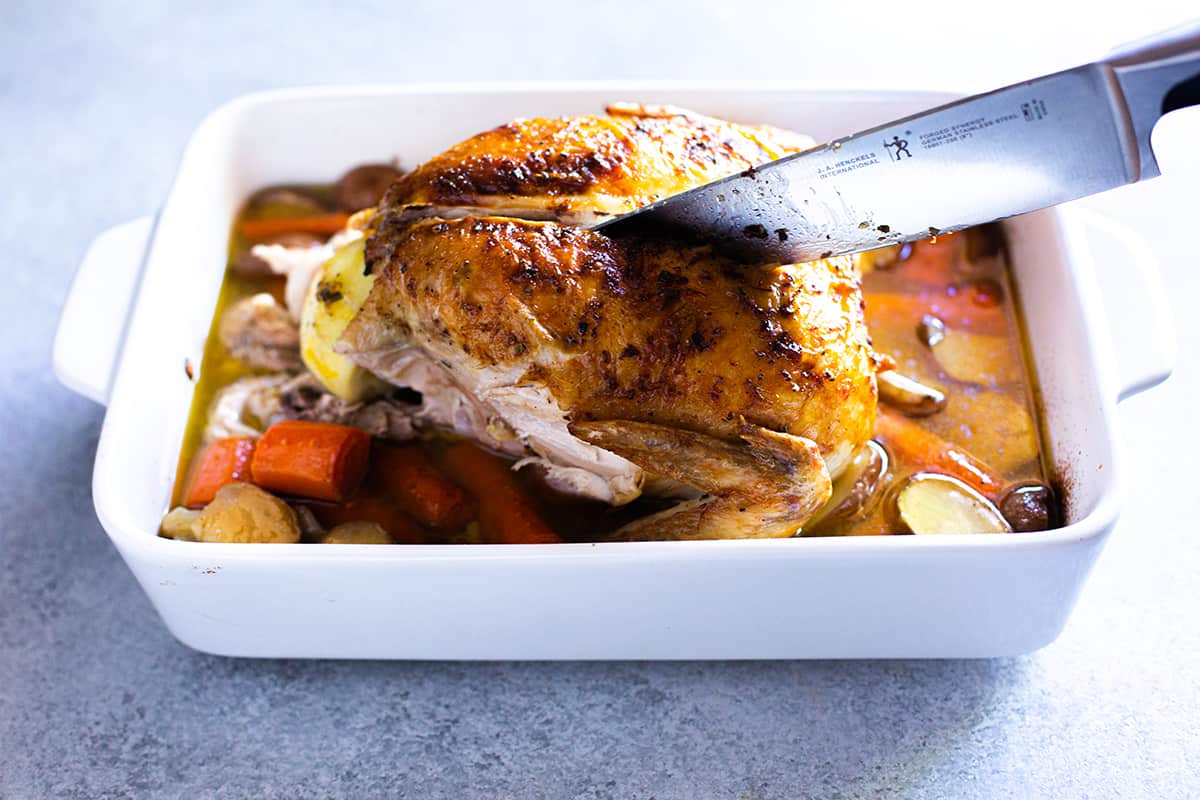 Ayam panggang yang diukir dengan pisau besar, di tengah daging dada.