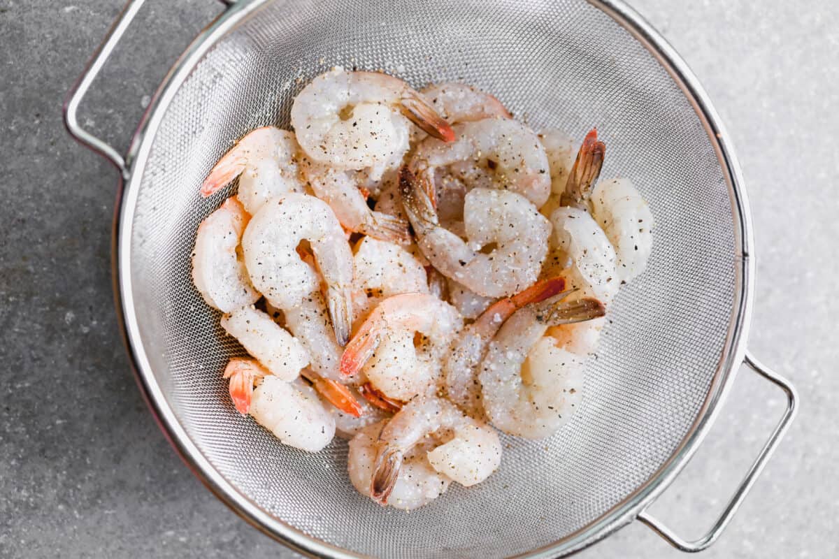 Raw shrimp just thawed and rinsed, resting in a colander. 