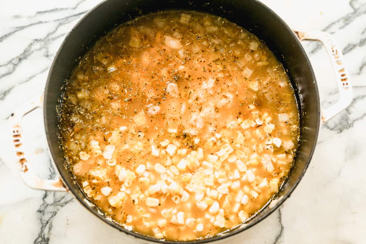 Kaldu dengan bawang potong dadu dan rempah-rempah untuk membuat Cabai Ayam Putih buatan sendiri.