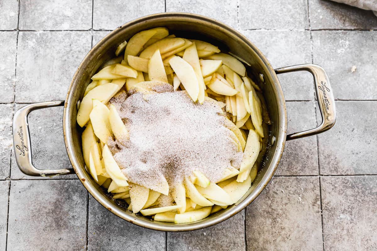A pot filled with peeled and sliced apples, and all the spices for Apple Pie filling. 