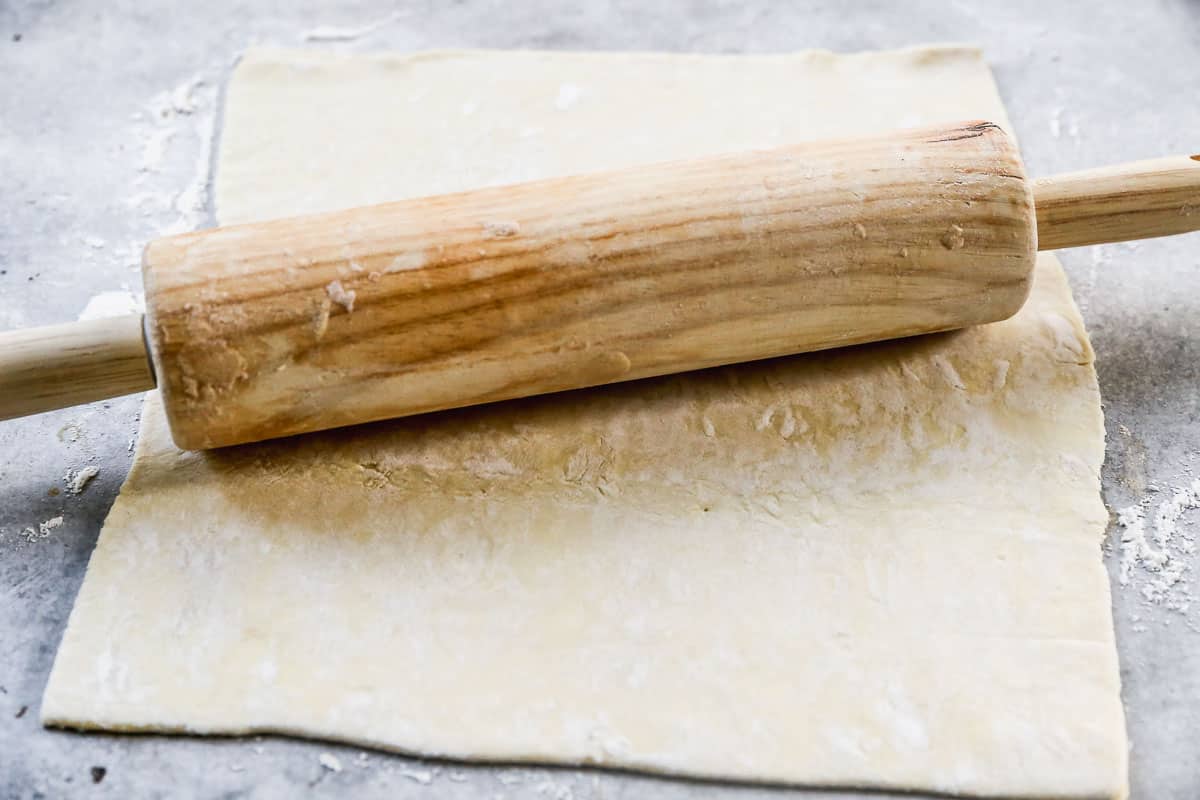 Puff Pastry being rolled out with a wooden rolling pin.