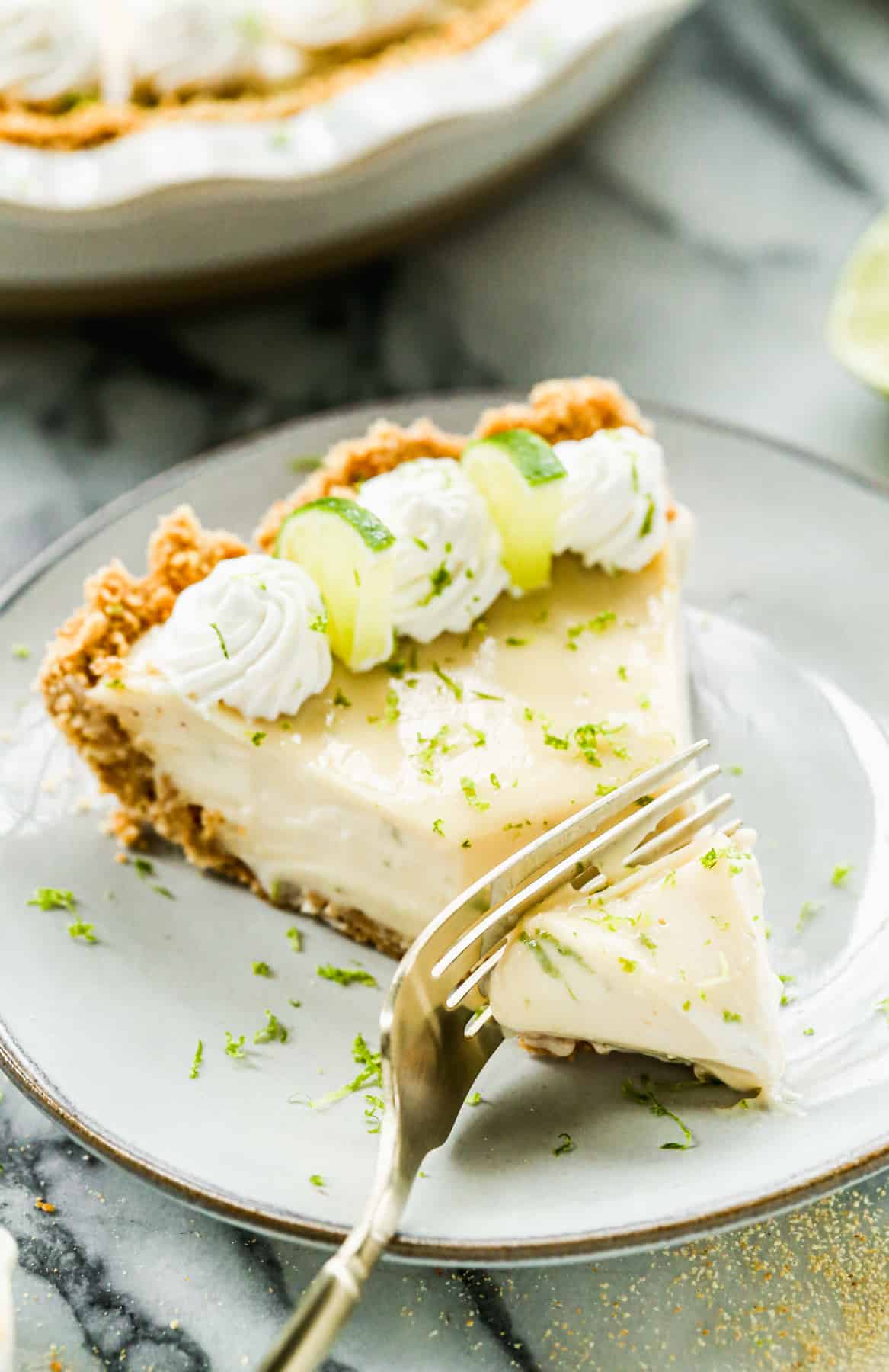 A fork cutting a bite of a piece of easy Key Lime Pie. 