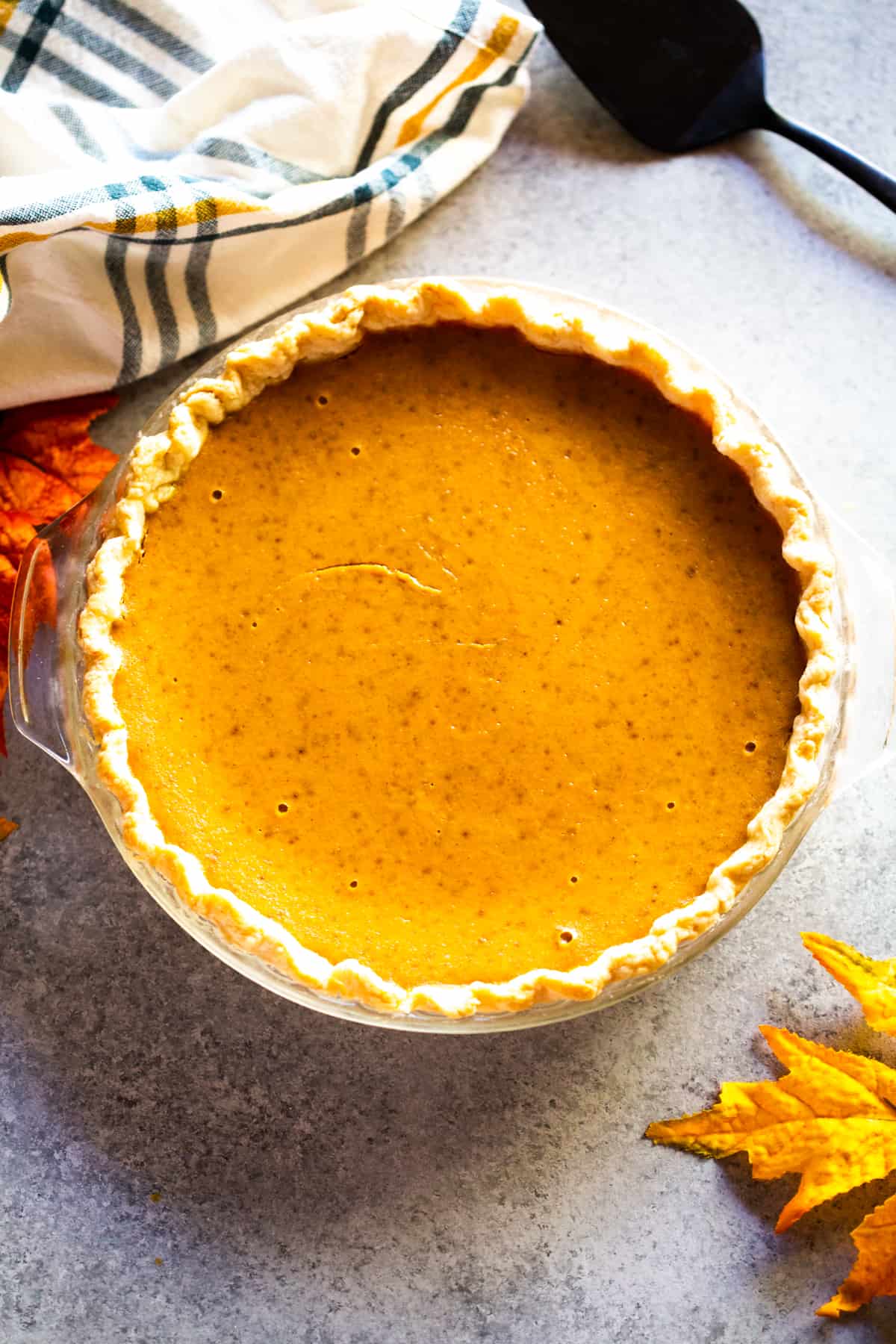 A homemade pumpkin pie in a pie pan, ready to slice and serve.