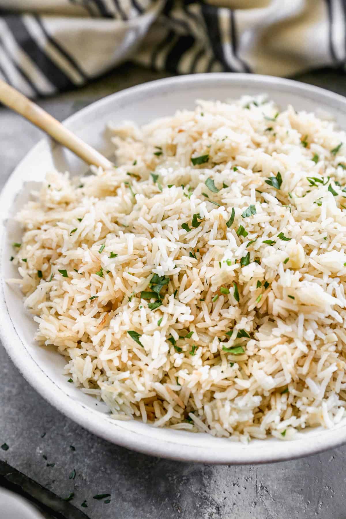 A close-up image of a bowl filled with homemade Rice Pilaf and sprinkled with fresh parsley. 