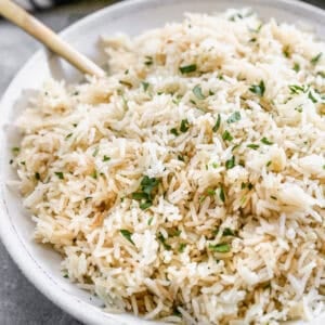 The best Rice Pilaf recipe in a large bowl with chopped parsley stirred in.