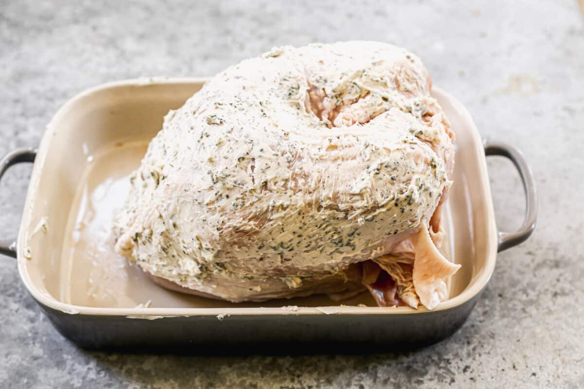 A Turkey with just breast meat in a baking dish covered with salt, pepper, and homemade herb butter.