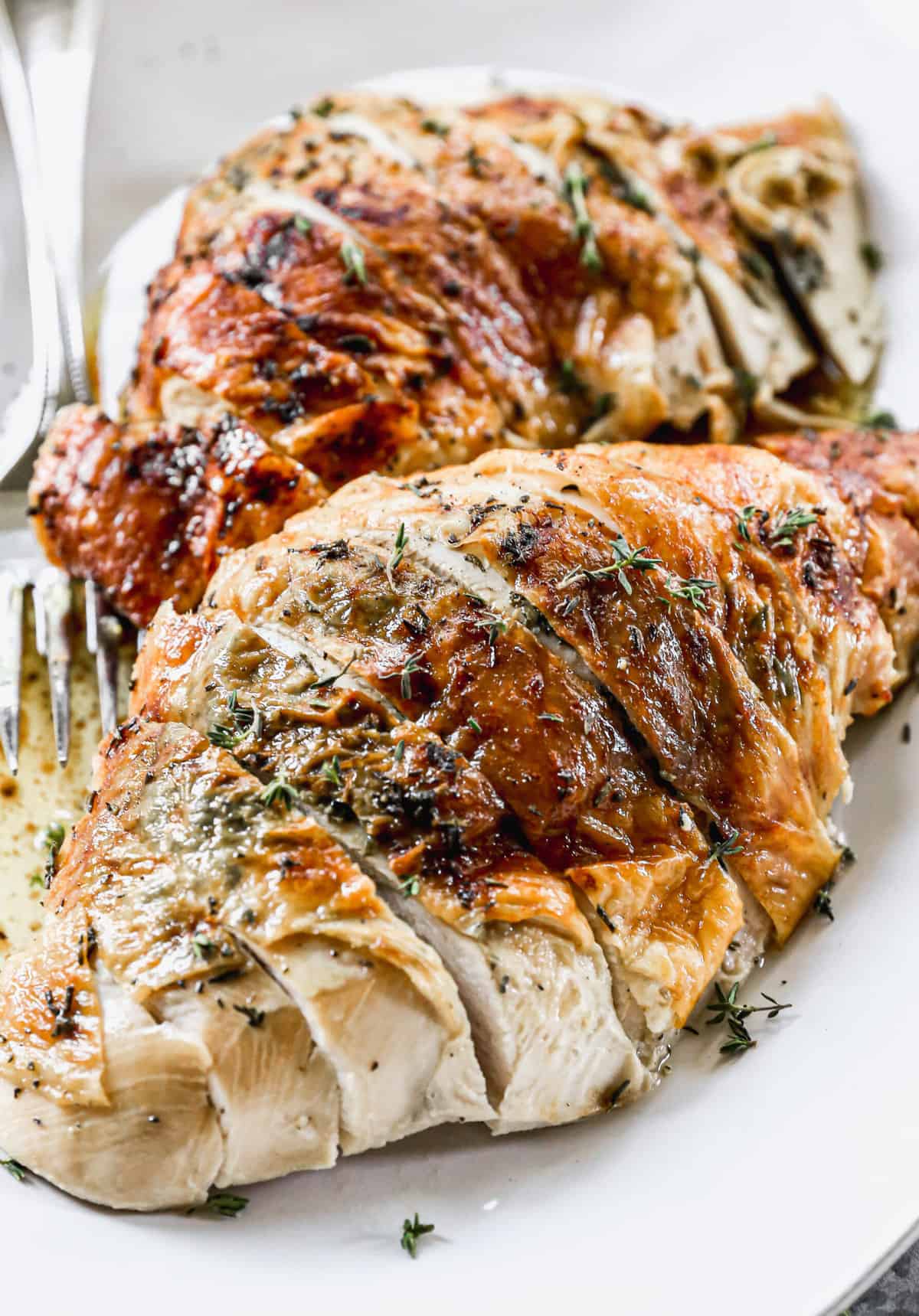 A close up image of a golden herb Roasted Turkey breast, sliced and ready to serve.