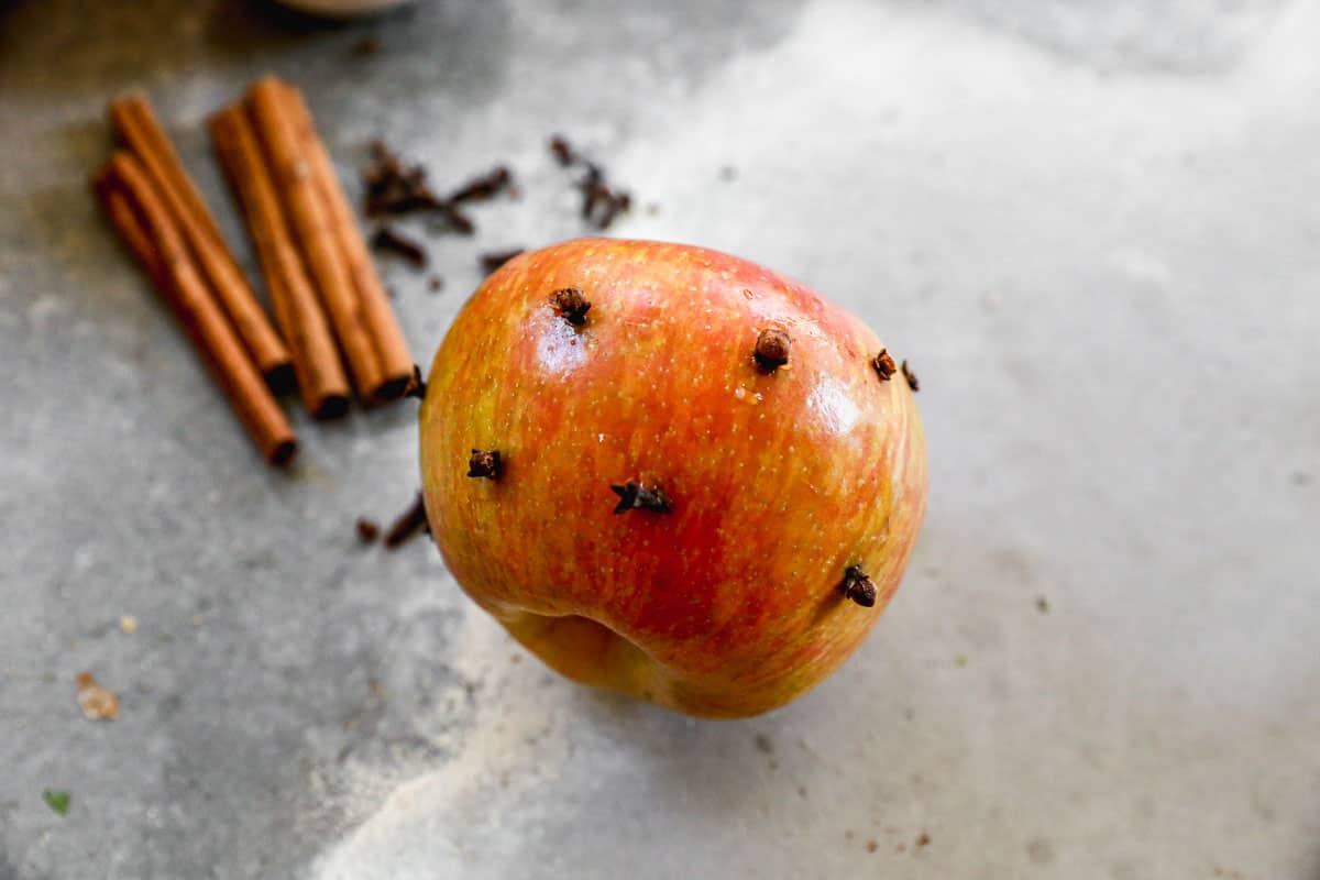 An apple with whole cloves poked into it, getting ready to make Wassail.