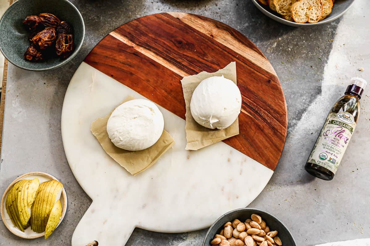 Two balls of burrata placed on a serving board.