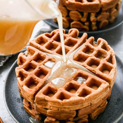 Vanilla syrup being poured on a stack of homemade Gingerbread Waffles.