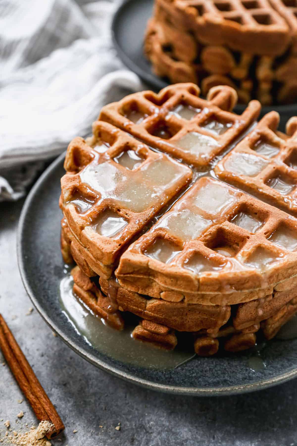 A close up image of a stack of Gingerbread Waffles with vanilla syrup poured on top.