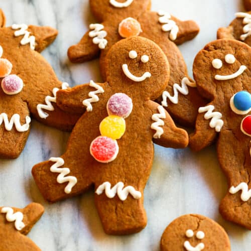 Homemade gingerbread men laying on a marble counter.