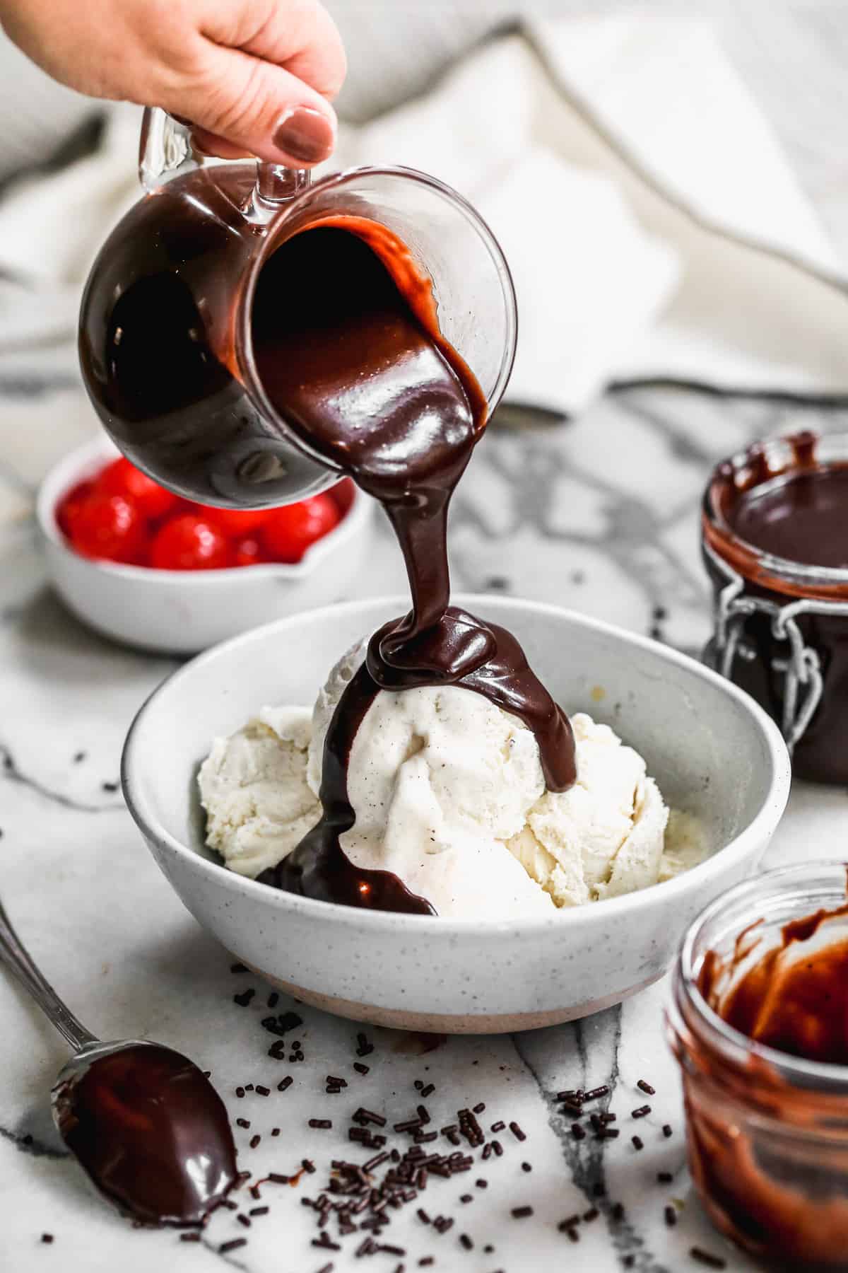Homemade Hot Fudge being poured on top of a bowl of vanilla ice cream.