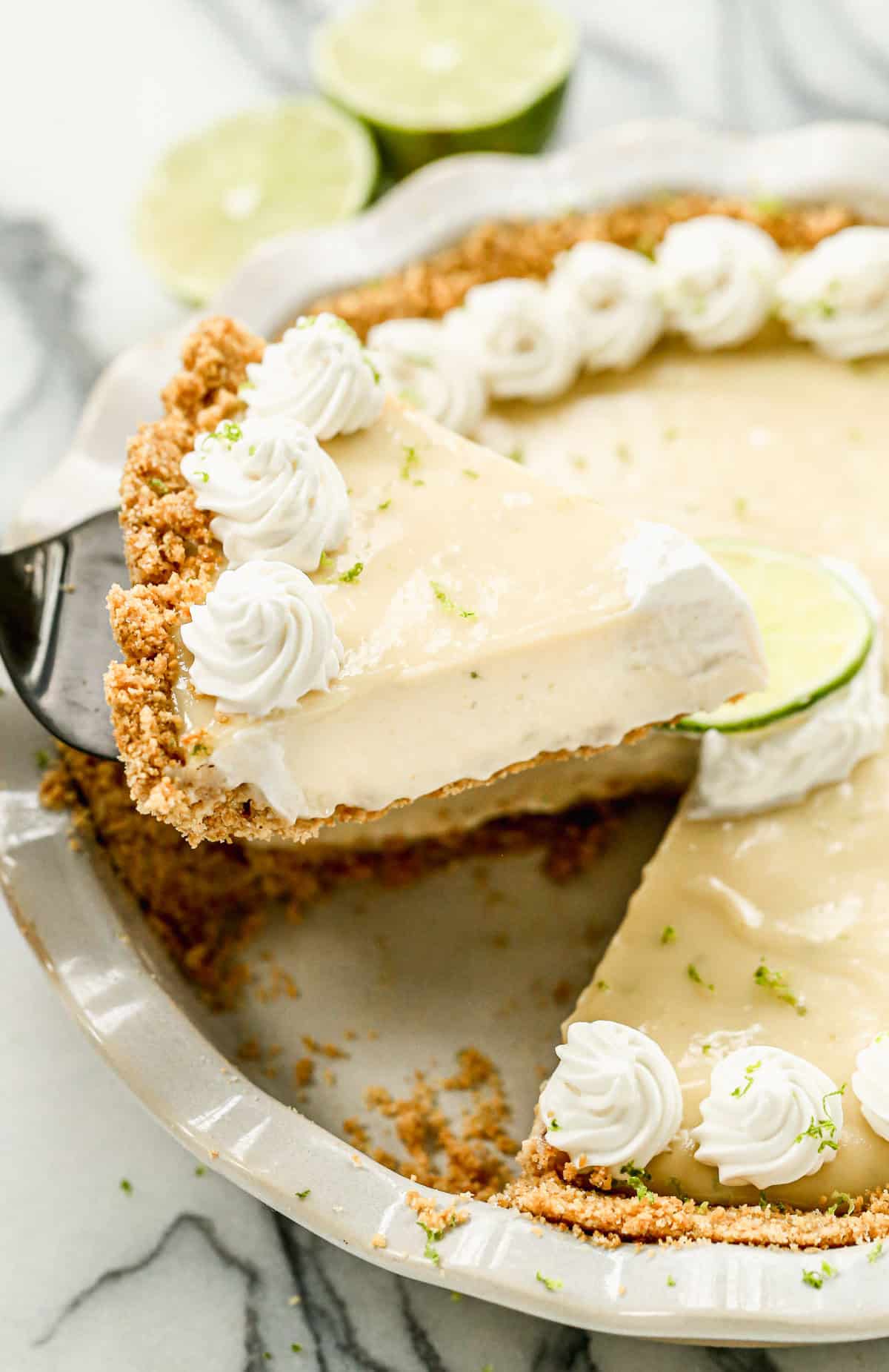An easy Key Lime Pie recipe with one slice being raised from the pie to serve. 