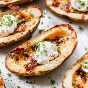 A close up image of Loaded Potato Skins topped with sour cream and chives, ready to serve.