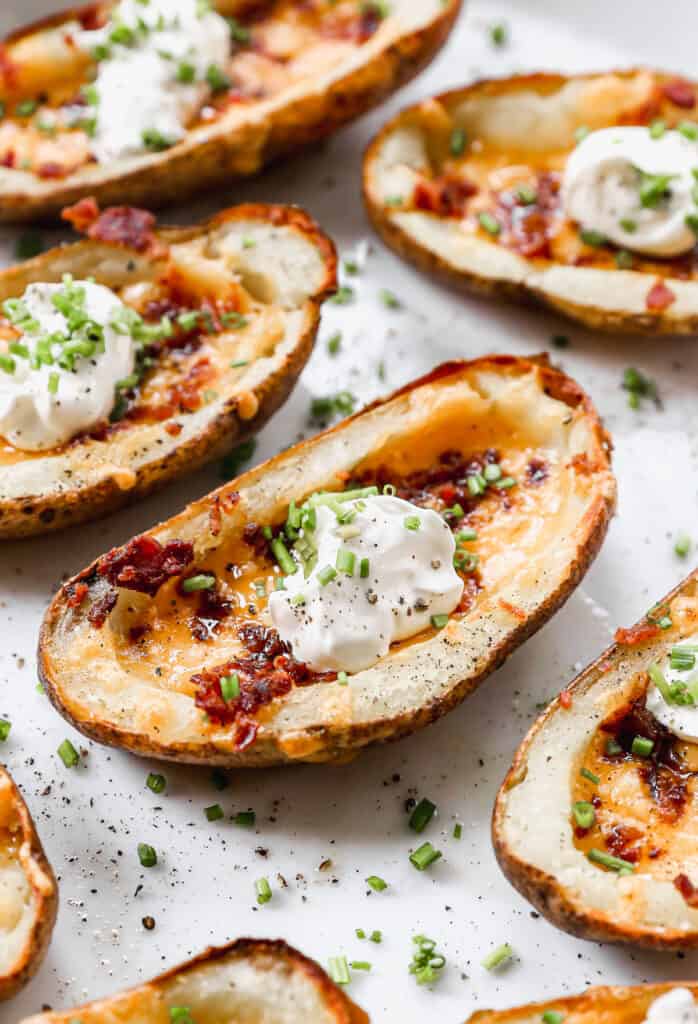 A close up image of Loaded Potato Skins topped with sour cream and chives, ready to serve.
