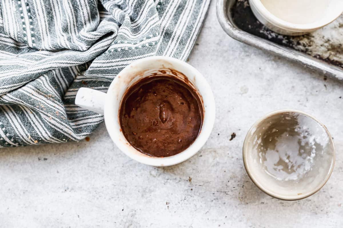 A white mug filled with the batter for a chocolate mug cake, ready to microwave.