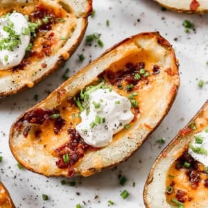 Crispy potato skins loaded with melted cheese, bacon, sour cream, and chives are everyone's favorite appetizer or side dish! Learn how to make potato skins at home!