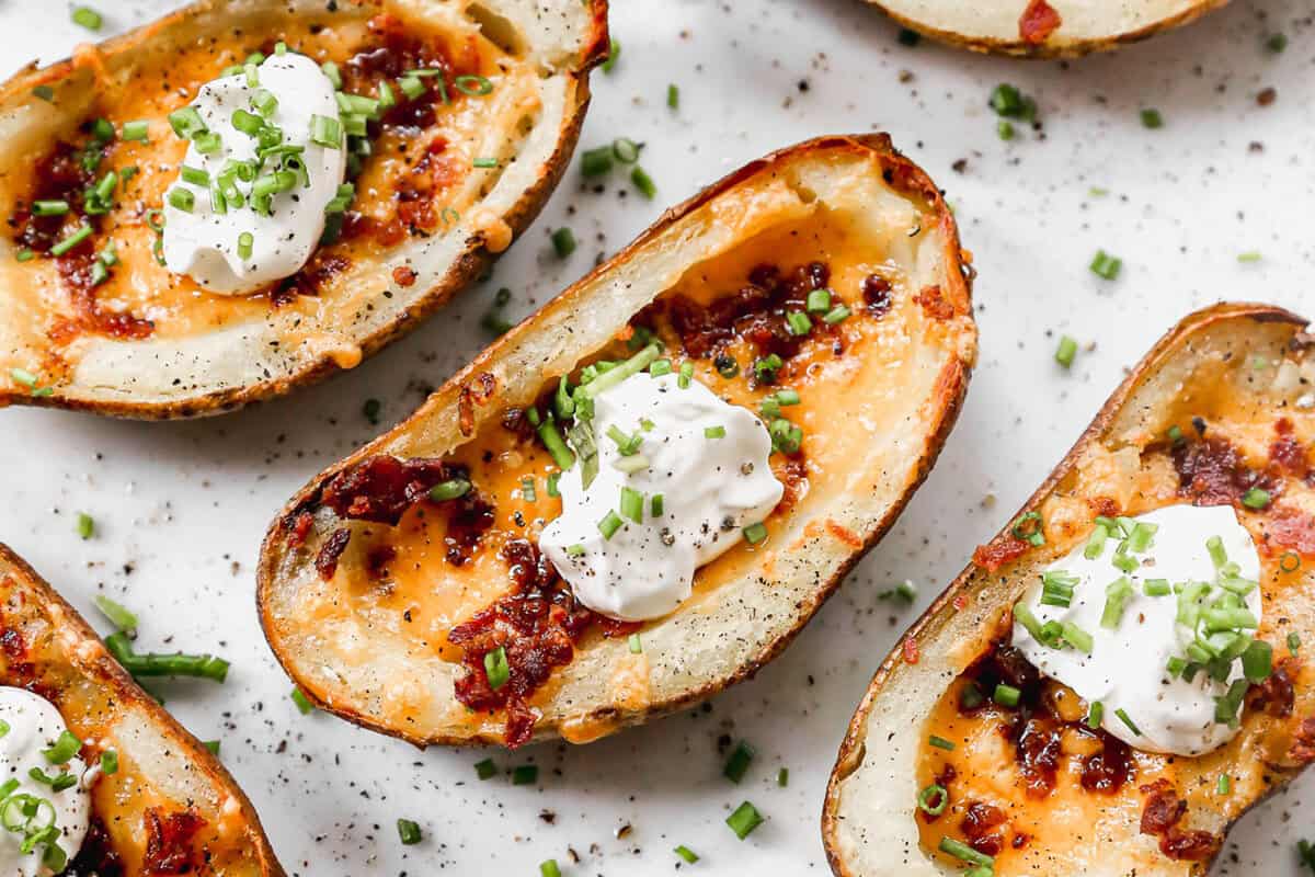 Crispy potato skins loaded with melted cheese, bacon, sour cream, and chives are everyone's favorite appetizer or side dish! Learn how to make potato skins at home!