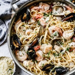 A pan filled with a creamy Seafood Pasta recipe loaded with shrimp, clams, mussels, and scallops.