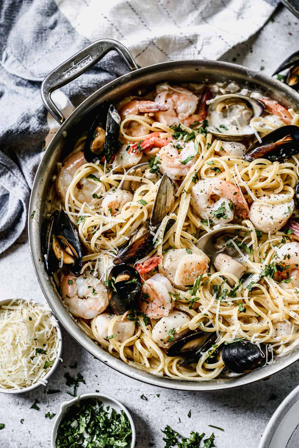A pan filled with a creamy Seafood Pasta recipe loaded with shrimp, clams, mussels, and scallops. 