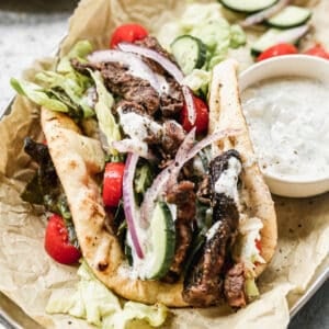 A homemade beef gyro wrapped in a warm pita and topped with lettuce, cucumber, red onion, tomato, and homemade tzatziki sauce.