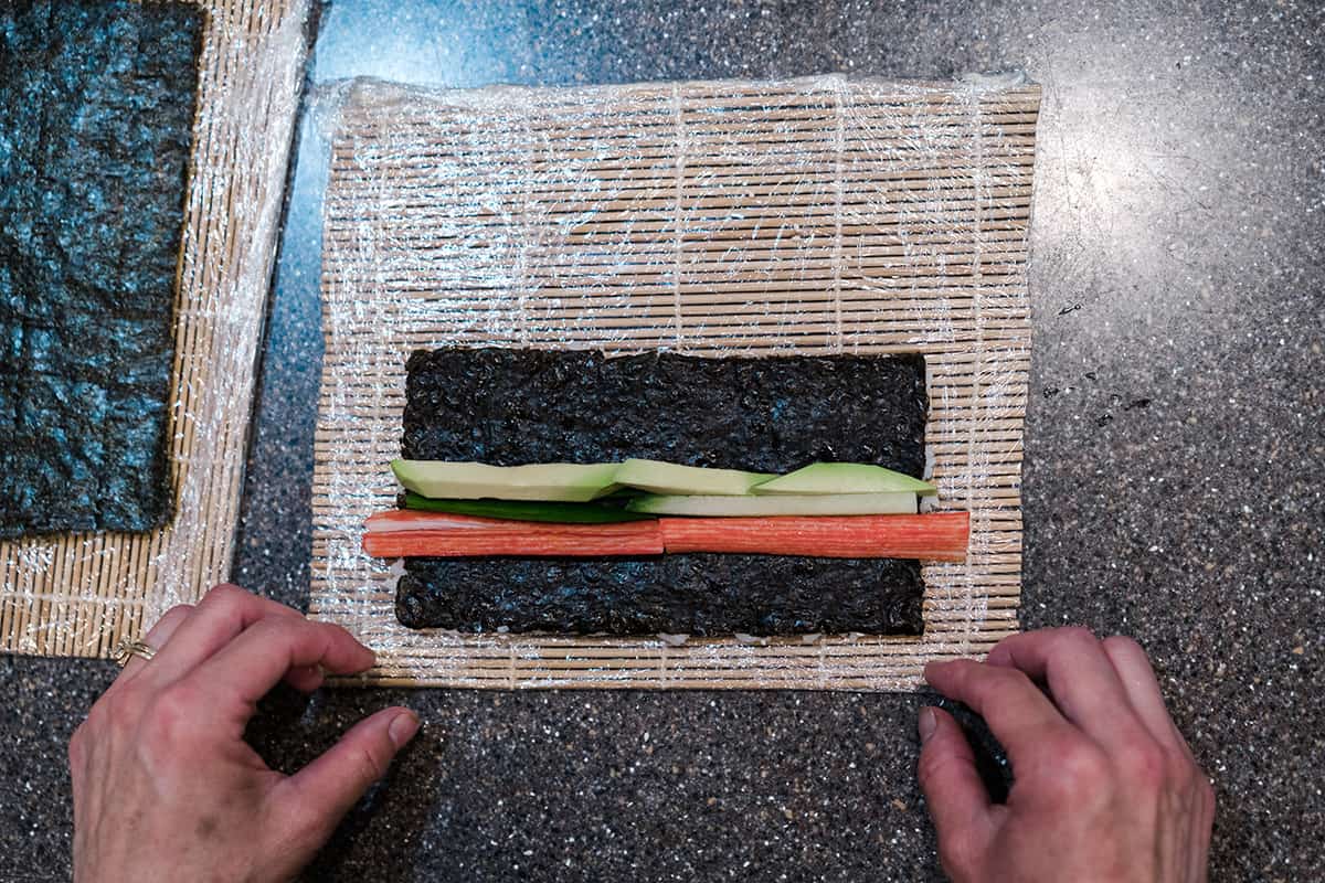 A California roll with cucumbers, avocado, and imitation crab stick, ready to be rolled.