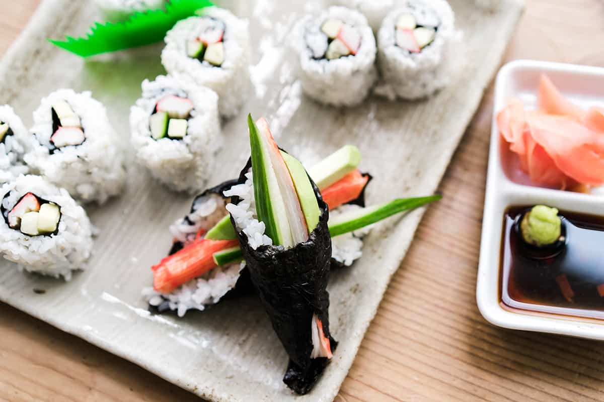 A plate of California Rolls with two Temaki Te (Sushi Hand Rolls) stacked in front.