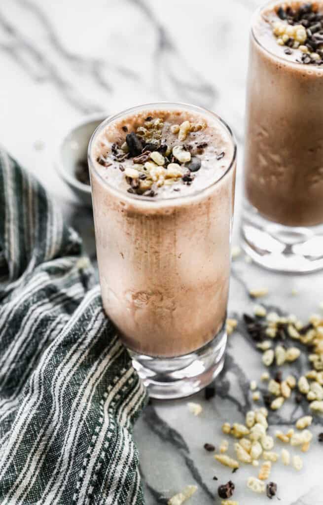 A Chocolate Protein Shake topped with cacoa nibs and rice crispy cereal, ready to enjoy.