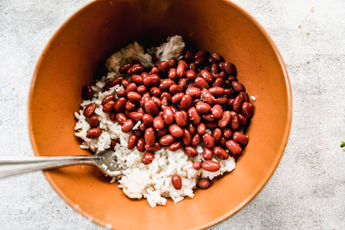Kacang merah diaduk menjadi nasi putih untuk membuat Jerk Chicken Bowls.