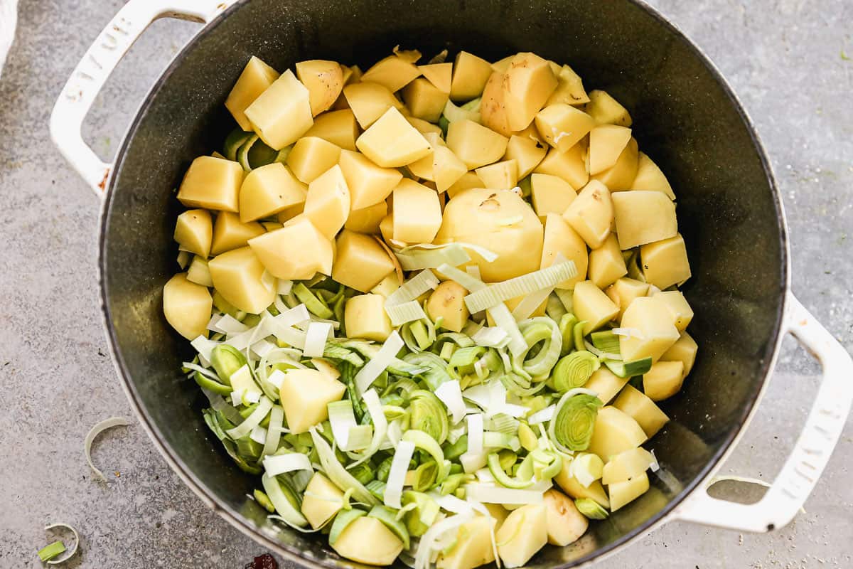 Kentang kupas dan cincang dan daun bawang cincang dalam panci sup besar untuk membuat Sup Bawang dan Kentang buatan sendiri.